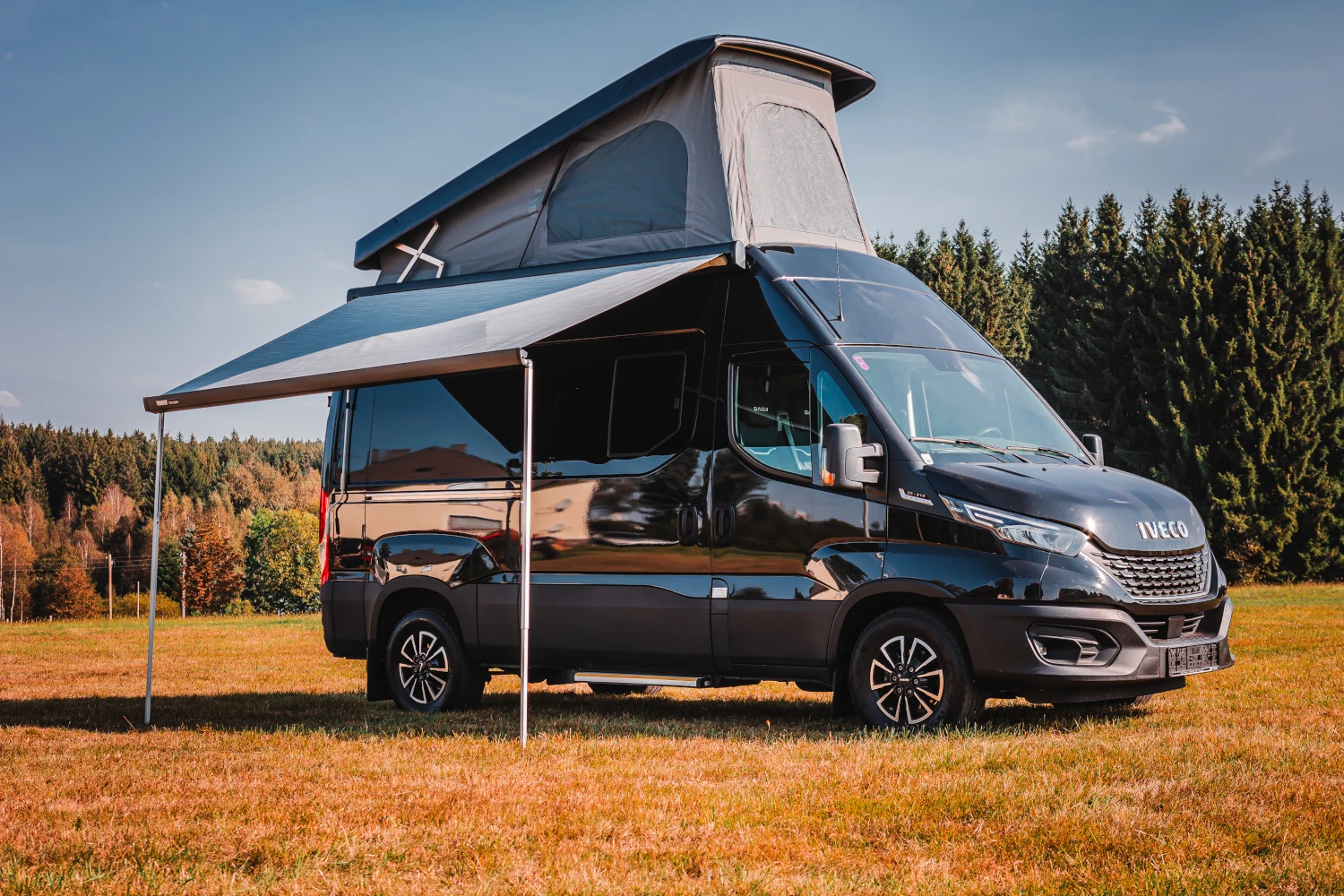 Iveco Daily mit offenen Aufstelldach und herausgefahrener Markise - seitliche Frontalansicht